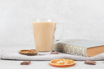 Coffee, orange slices, chocolate and book on cloth