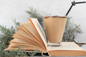 Glass of tasty coffee on open book