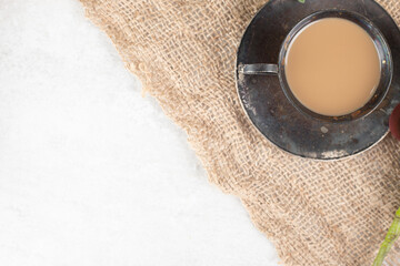 Cup of hot coffee with saucer on burlap