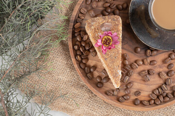Slice of cake, coffee and coffee beans on wooden plate