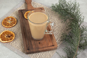 Glass of coffee on wooden board with orange slices