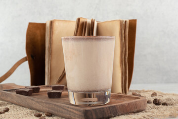 Coffee and chocolate pieces on wooden board with beans and notebook