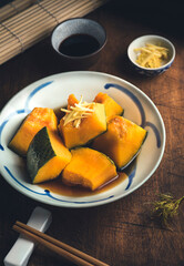  Autumnal  Kabocha Squash (Japanese Pumpkin) recipe. Japanese Simmered Kabocha cooked in savory dashi broth seasoned with soy sauce and sake with pumpkin seeds, close up, wooden rustic background