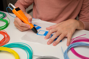 Teen Girl Using 3d Pen. Printing with Colored Plastic Wire Filament. Child making a House, drawing with 3D pen. Artwork, Robotics. STEAM, STEM education. Modern Technologies. Play and study at home