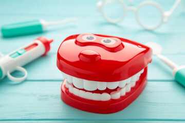 Model toys teeth with dentist instrument on blue background.