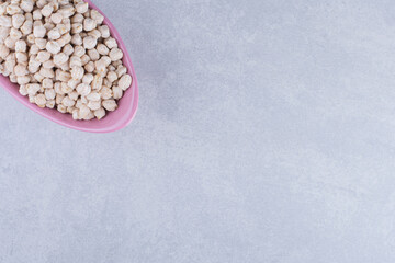 Small heap of chickpeas filled into a violet bowl on marble background