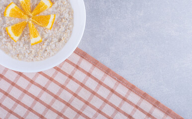 Platter of oatmeal topped with orange slices on marble background