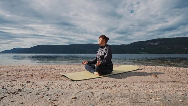 Young woman is practicing yoga between mountains in Norway telemark