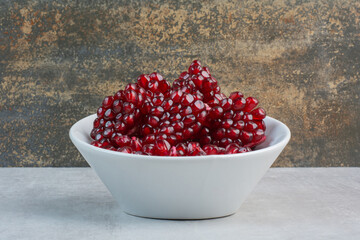 Red pomegranate seeds in white bowl