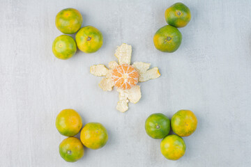 Peeled and unpeeled fresh tangerines on stone surface