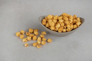 Appetizer bowl filled with a serving of caramel coated popcorn on marble background