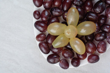Purple and green grapes on white plate
