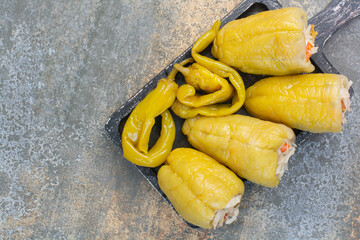 A dark board with salty peppers and cabbage on white background