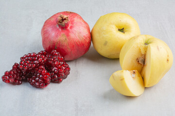 Pomegranate and quinces on stone background