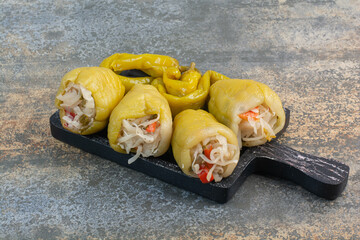 A dark board with salty peppers and cabbage on white background