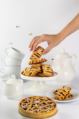 Scary shortbread cookies with jam for Halloween. On a white background, sugar sprinkled bones and cast eyes. White dishes with sweets.