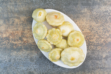 A white plate of delicious fruits on marble background