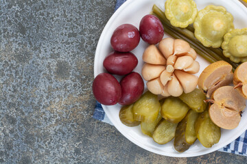 A white plate full of salty vegetables on tablecloth