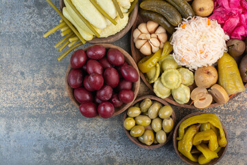 Salty vegetables in wooden bowls on marble background