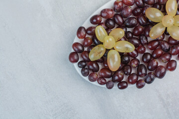 Purple and green grapes on white plate