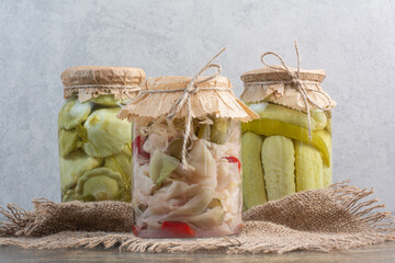 Three jars full of salty vegetables on sackcloth