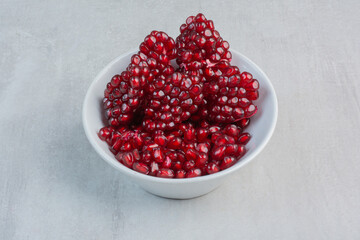 Red pomegranate seeds in white bowl