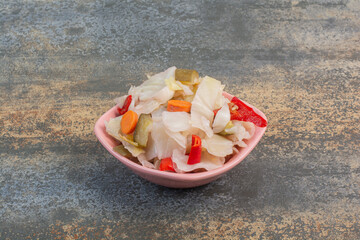 A pink plate full of salty vegetables on marble background