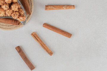 Platter of flavored popcorn next to arrangement of cinnamon cuts on marble background