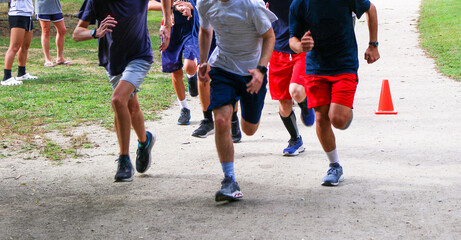 Group of runners running together on a dirt path in a park