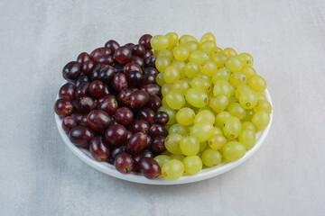 Bunch of purple and green grapes on white plate