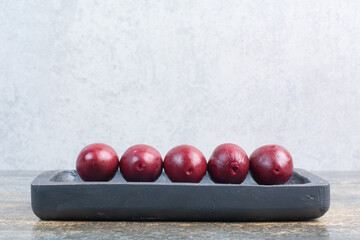 Delicious sweet fruits in dark board on marble background