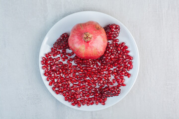 Pomegranate and pomegranate seeds on white plate