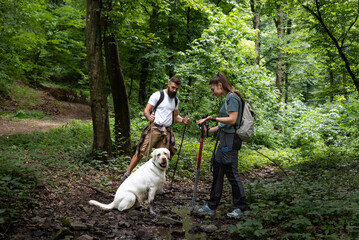 Young adventurer couple man and woman cant have children so they adopt young dog Labrador Retriever puppy and explore forest with him by walking in the nature.