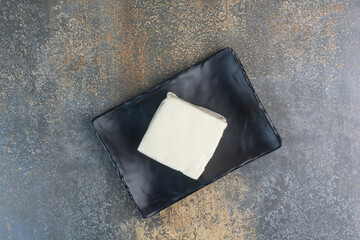 Natural white cheese on black plate