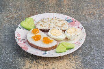 Tasty breakfast plate with bread and eggs on marble surface