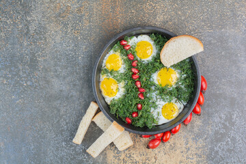 Obraz na płótnie Canvas Fried eggs with dill, pomegranate seeds and bread slices