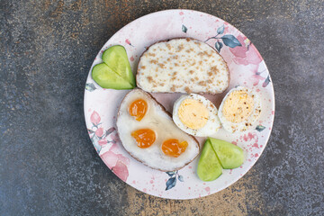 Breakfast plate with bread and eggs on marble surface