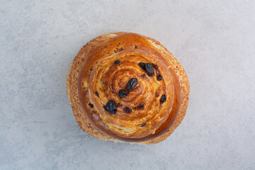 Homemade bun with raisins on gray background