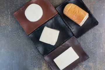 Different kinds of cheese on dark plates