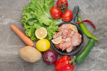 Fresh vegetables with raw chicken on marble background