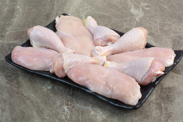 Fresh unprepared chicken legs on dark plate
