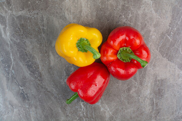Three whole peppers on marble background