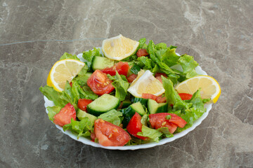 Vegetable salad with slices of lemon on white plate