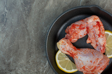 Raw chicken meat with spices and lemon on dark pan