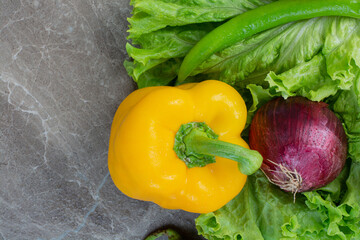 Fresh onion, pepper and lettuce on marble background