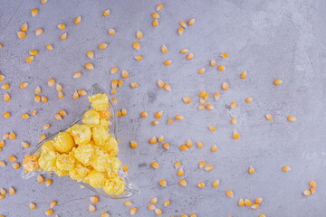 Flavored popcorn in a triangular platter with corn kernels scattered around on marble background