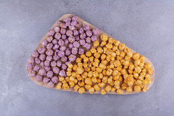 Large tray with assorted flavors of popcorn candy heaped on top on marble background