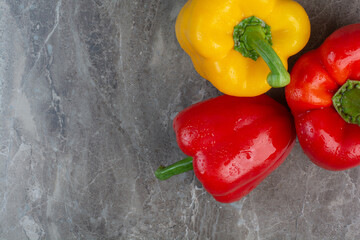 Three whole peppers on marble background