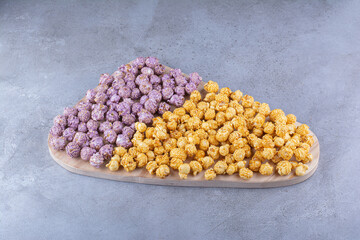 Large tray with two kinds of popcorn candy heaped on top on marble background