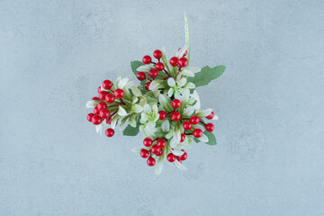 Artificial flowers with berries on blue background